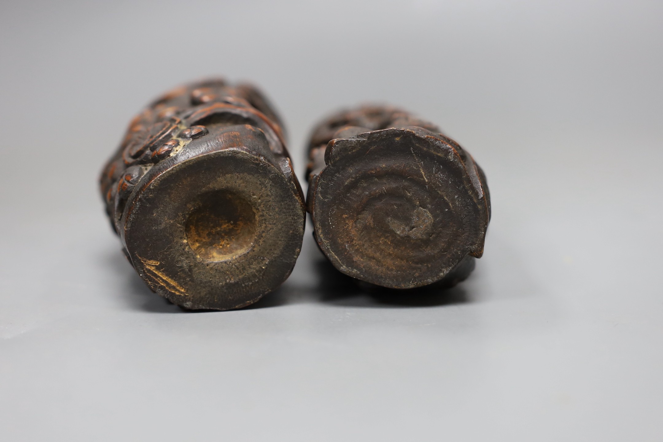 A pair of Chinese carved bamboo brush pots, late Qing dynasty, carved in high relief with a sage beneath a prunus tree, 11cms high